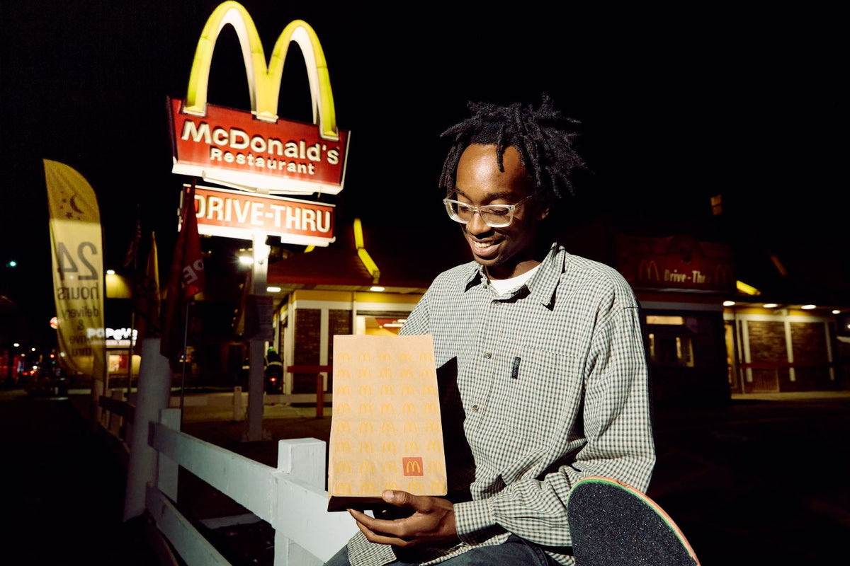 Extrait du film de la campagne : un homme porte un skateboard McDonald's rouge devant les néons Frites, Arches dorées et McFlurry